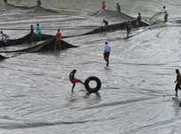 Sri Lankan ground staff cover the pitch with plastic sheeting as rain stops play.